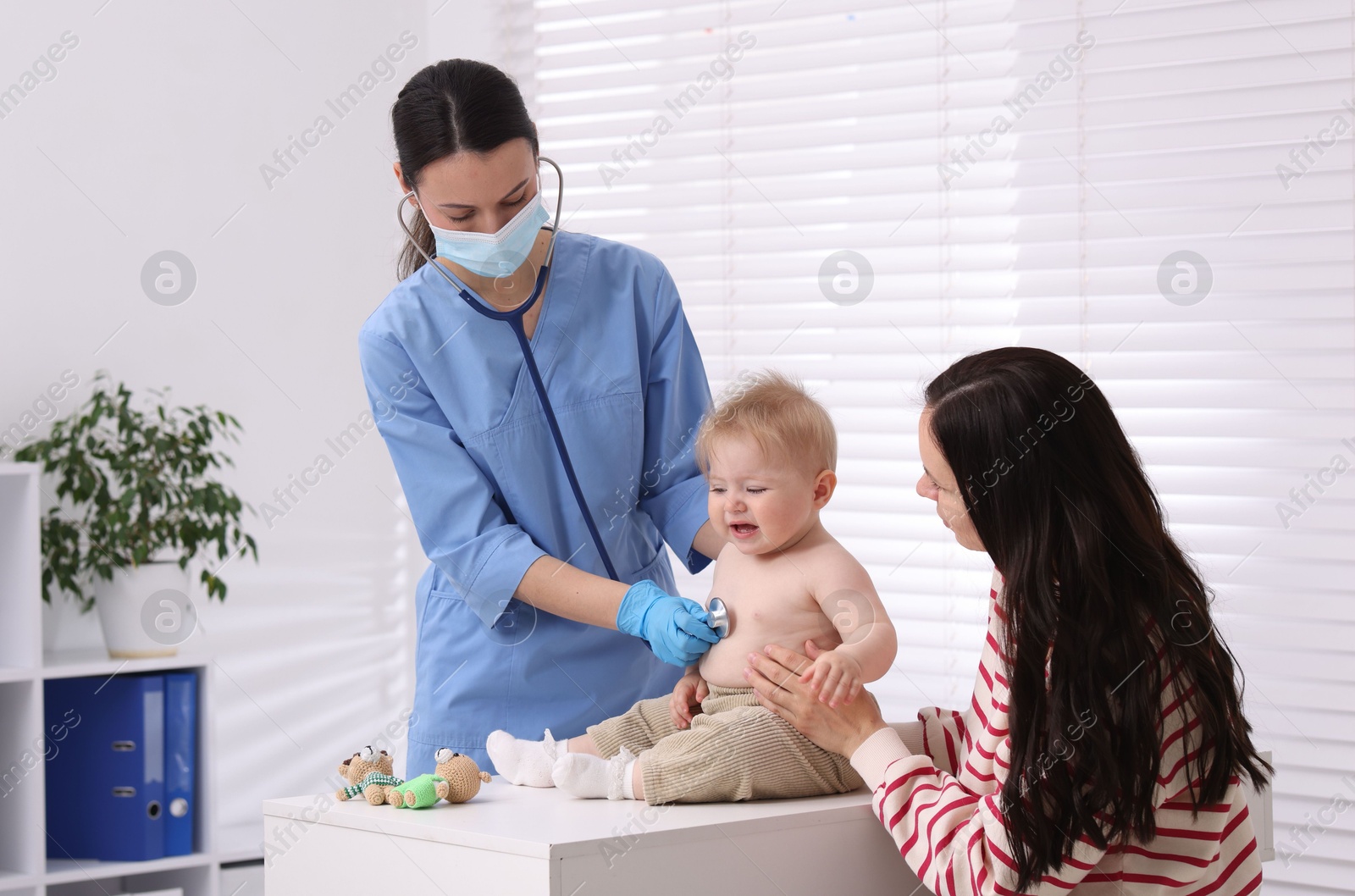 Pediatrician examining baby with stethoscope in clinic Photo of Pediatrician examining baby with stethoscope in clinic