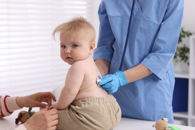 Photo of Pediatrician examining baby with stethoscope in clinic, closeup