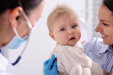 Photo of Pediatrician examining baby with stethoscope in clinic, closeup