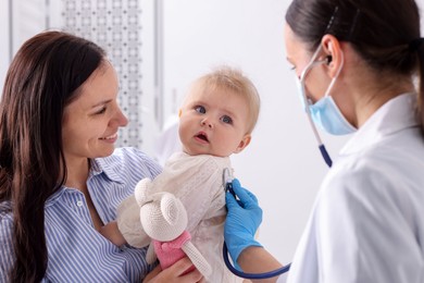 Photo of Pediatrician examining baby with stethoscope in clinic