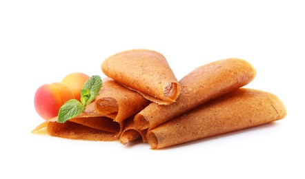 Photo of Delicious fruit leather rolls and apricots isolated on white
