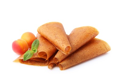 Photo of Delicious fruit leather rolls and apricots isolated on white