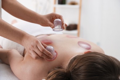 Photo of Therapist giving cupping treatment to patient in spa salon, closeup