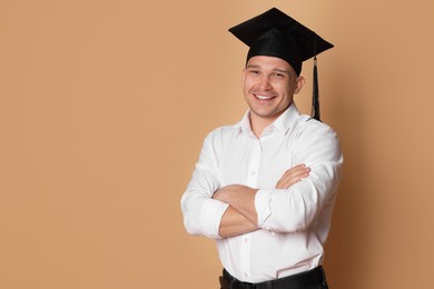 Photo of Happy student with crossed arms after graduation on beige background. Space for text
