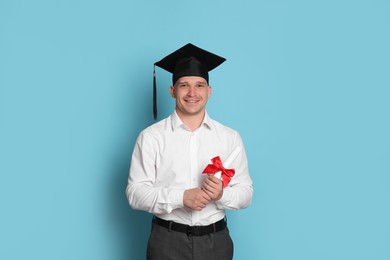 Photo of Happy student with diploma after graduation on light blue background