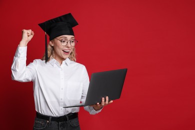 Photo of Happy student with laptop after graduation on red background. Space for text