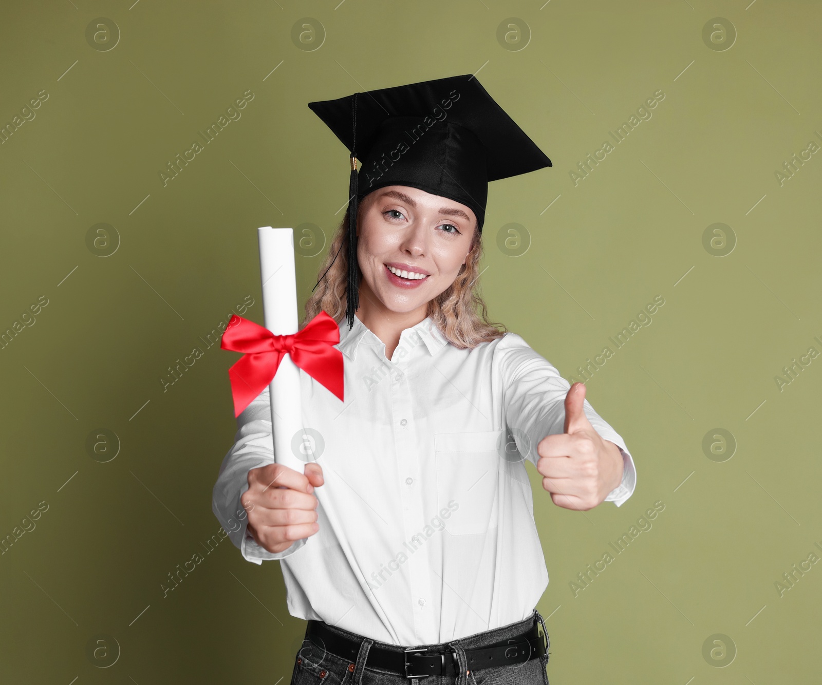 Happy student with diploma showing thumbs up after graduation on green background Photo of Happy student with diploma showing thumbs up after graduation on green background