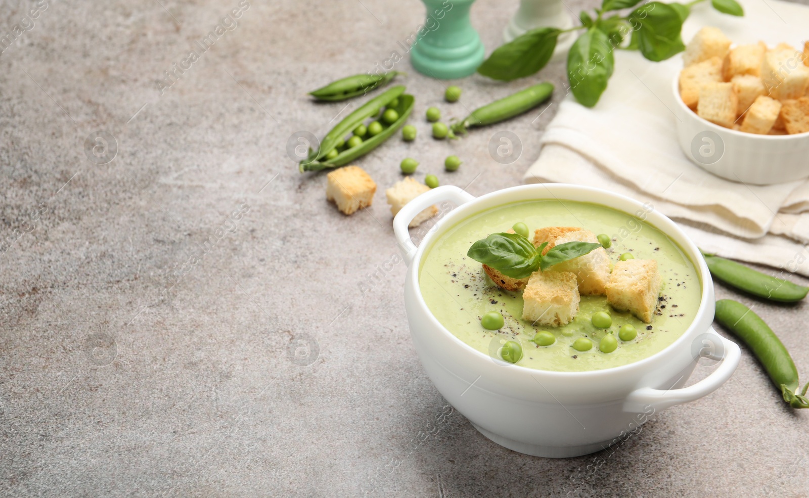 Tasty pea cream soup with croutons and basil served on grey table. Space for text Photo of Tasty pea cream soup with croutons and basil served on grey table. Space for text