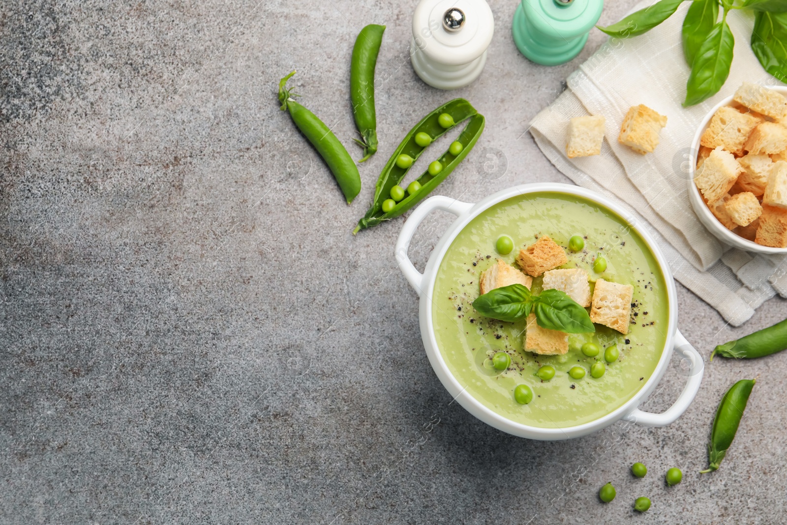 Tasty pea cream soup with croutons and basil served on grey table, flat lay. Space for text Photo of Tasty pea cream soup with croutons and basil served on grey table, flat lay. Space for text