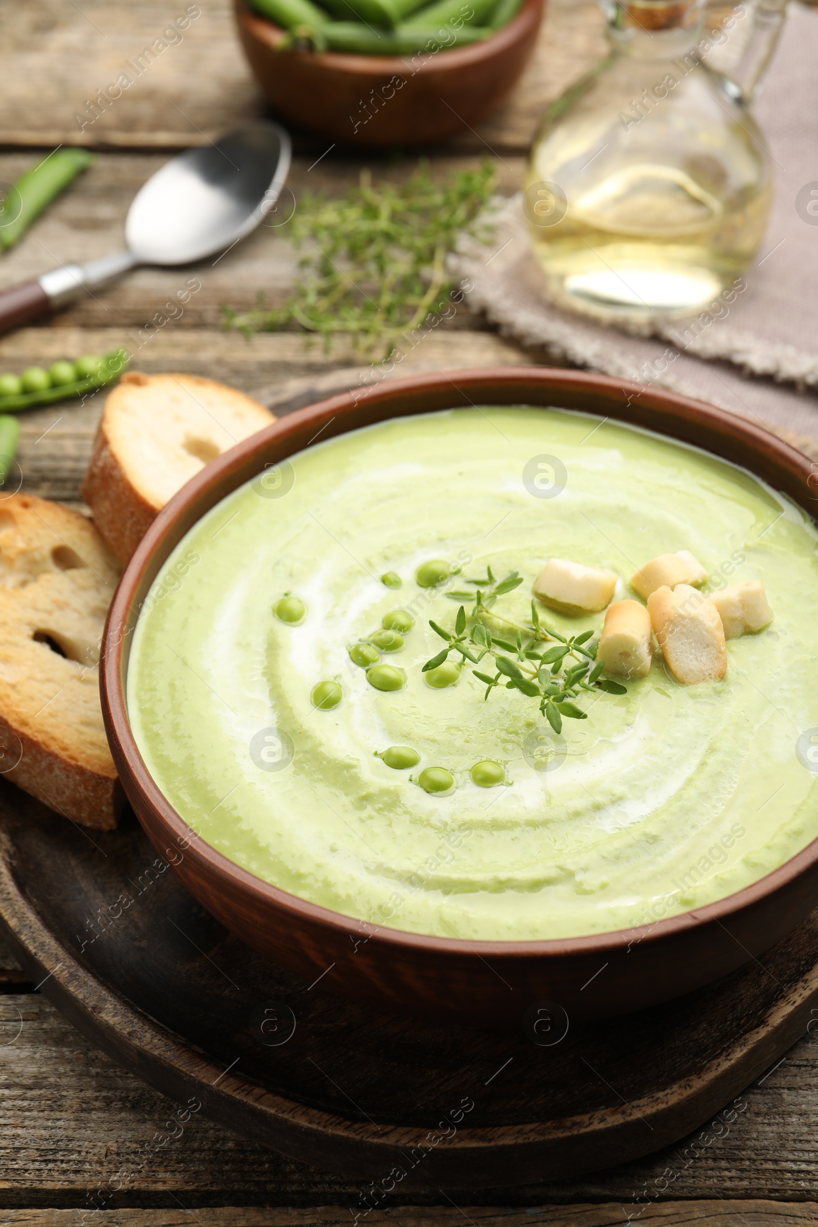 Tasty pea cream soup with croutons and thyme served on wooden table, closeup Photo of Tasty pea cream soup with croutons and thyme served on wooden table, closeup