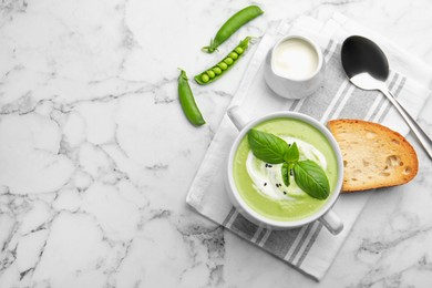 Photo of Tasty pea cream soup with basil served on white marble table, flat lay. Space for text