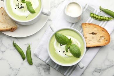 Photo of Tasty pea cream soup with basil served on white marble table, flat lay