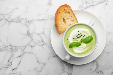 Photo of Tasty pea cream soup with basil served on white marble table, top view. Space for text