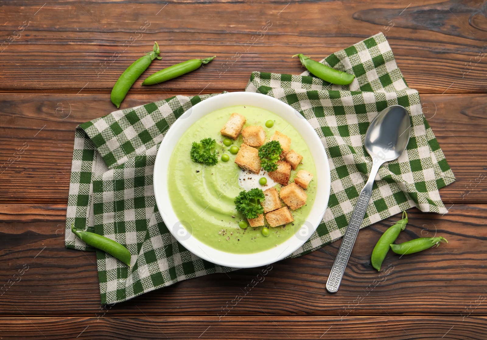 Tasty pea cream soup with croutons and broccoli served on wooden table, flat lay Photo of Tasty pea cream soup with croutons and broccoli served on wooden table, flat lay