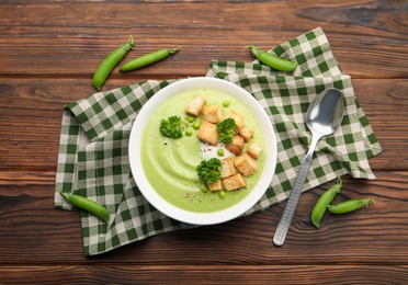 Photo of Tasty pea cream soup with croutons and broccoli served on wooden table, flat lay