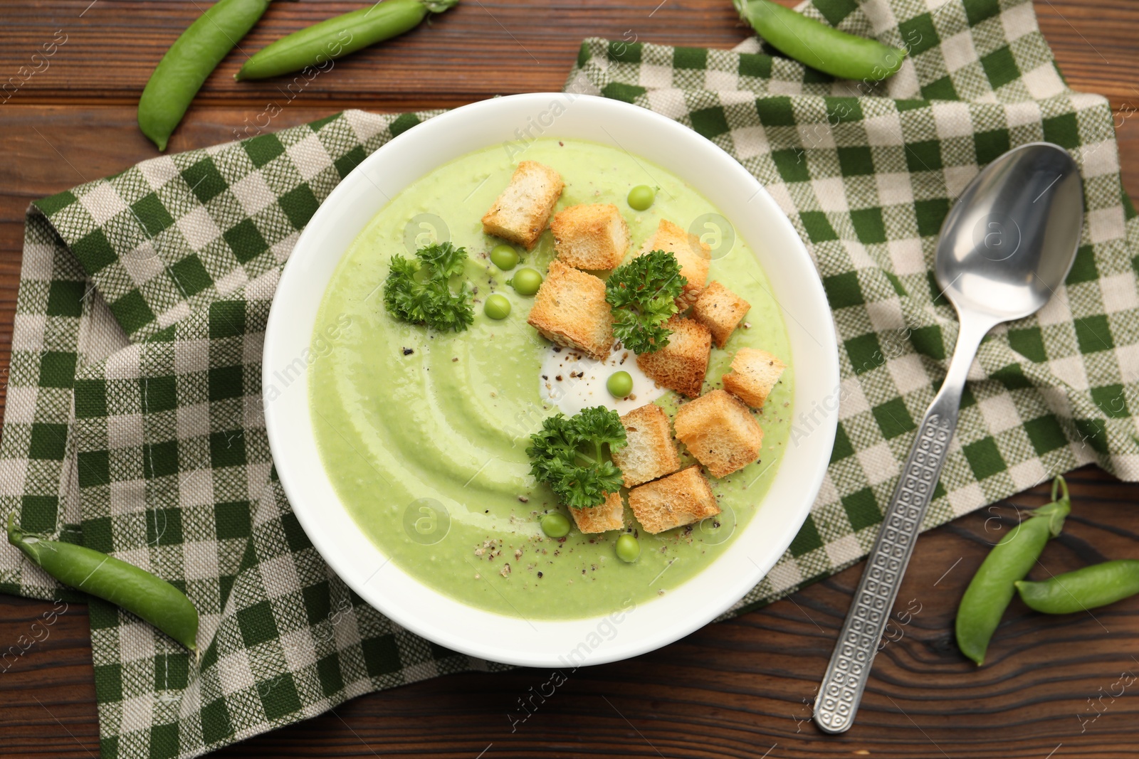 Tasty pea cream soup with croutons and broccoli served on wooden table, flat lay Photo of Tasty pea cream soup with croutons and broccoli served on wooden table, flat lay