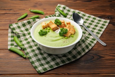 Photo of Tasty pea cream soup with croutons and broccoli served on wooden table