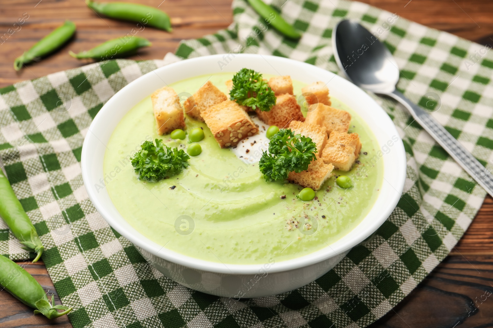 Tasty pea cream soup with croutons and broccoli served on wooden table, closeup Photo of Tasty pea cream soup with croutons and broccoli served on wooden table, closeup