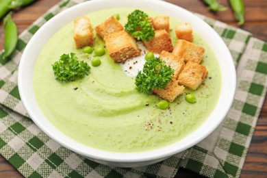 Photo of Tasty pea cream soup with croutons and broccoli served on wooden table, closeup