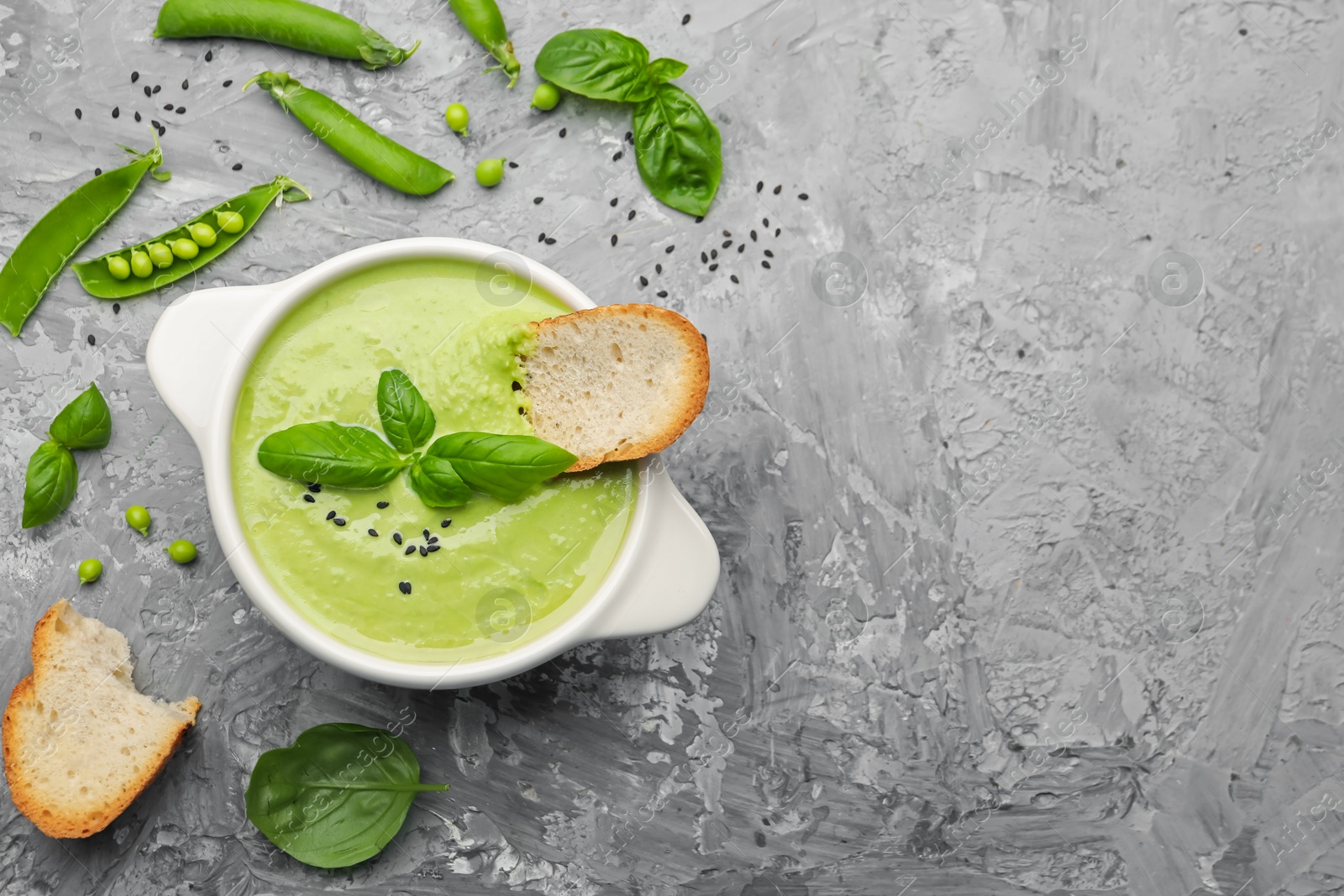 Tasty pea cream soup with basil and crouton served on grey table, flat lay. Space for text Photo of Tasty pea cream soup with basil and crouton served on grey table, flat lay. Space for text