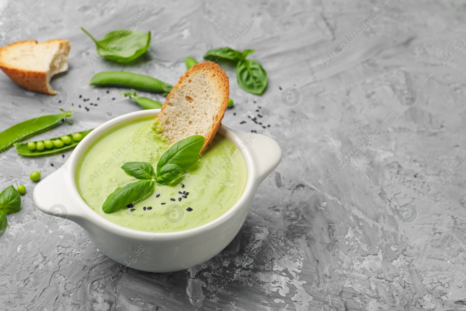Tasty pea cream soup with basil and crouton served on grey table. Space for text Photo of Tasty pea cream soup with basil and crouton served on grey table. Space for text
