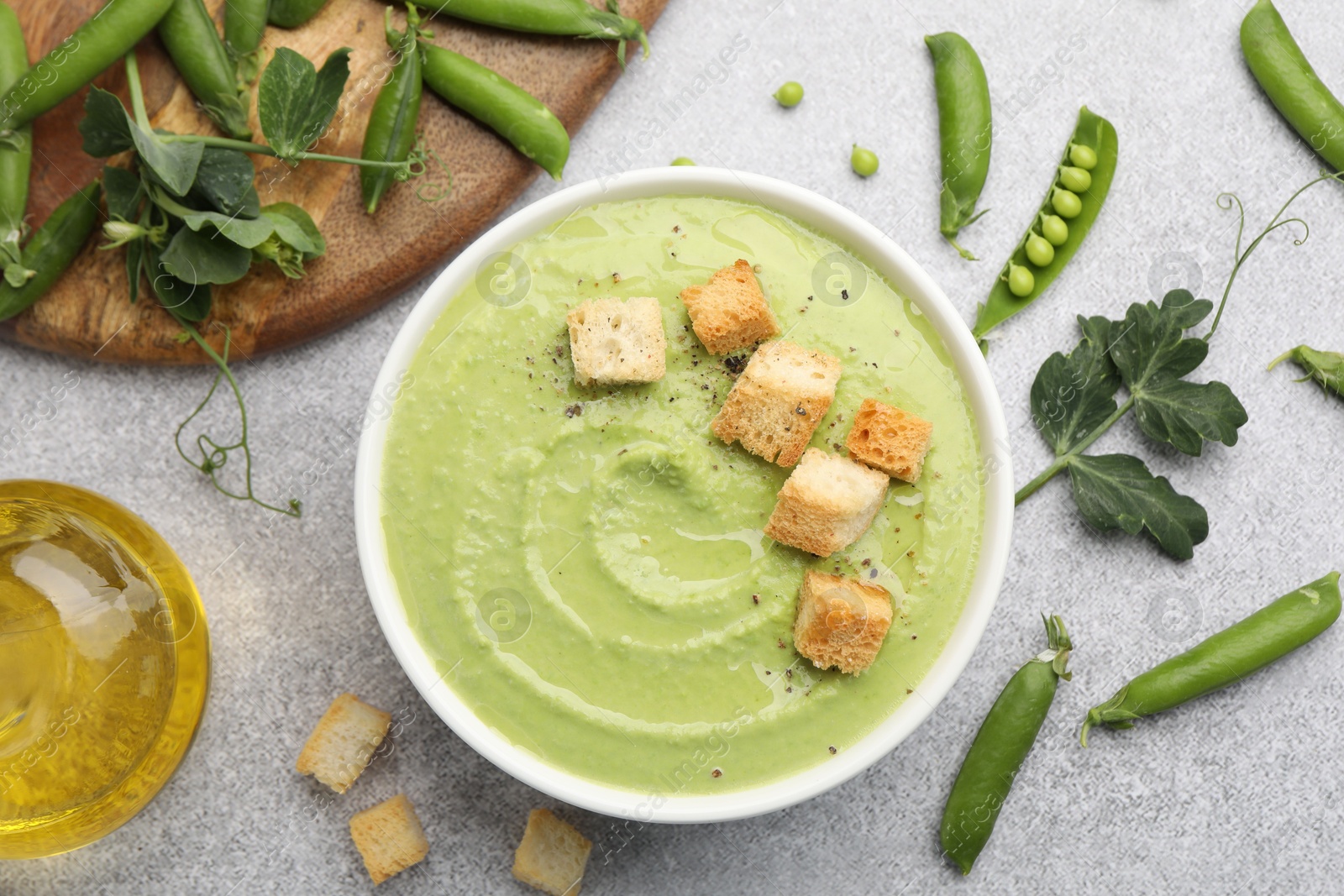 Tasty pea cream soup with croutons served on grey table, flat lay Photo of Tasty pea cream soup with croutons served on grey table, flat lay