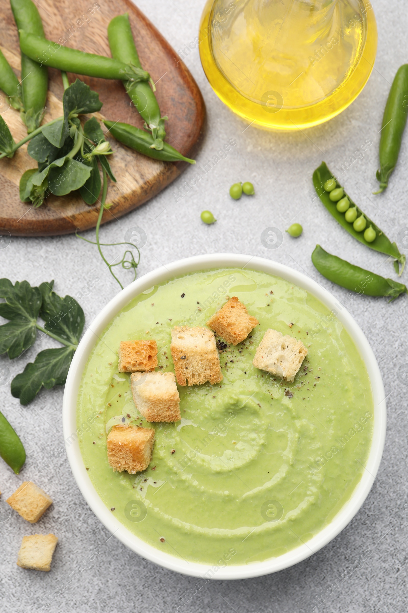 Tasty pea cream soup with croutons served on grey table, flat lay Photo of Tasty pea cream soup with croutons served on grey table, flat lay