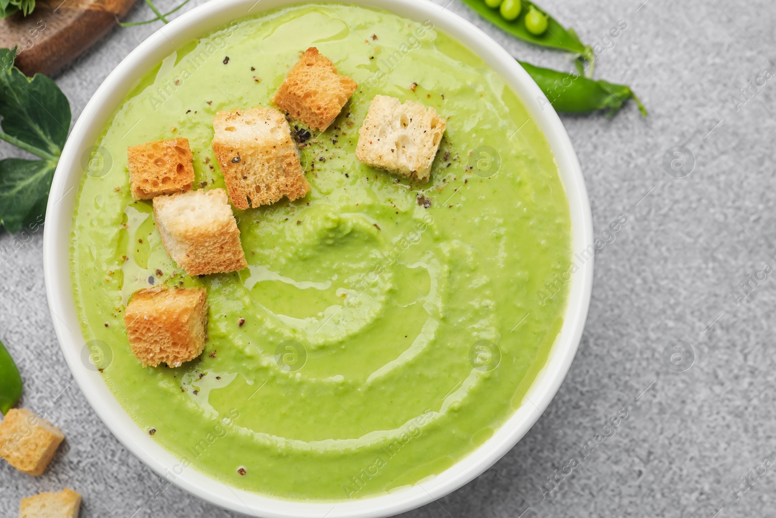 Tasty pea cream soup with croutons served on grey table, top view Photo of Tasty pea cream soup with croutons served on grey table, top view