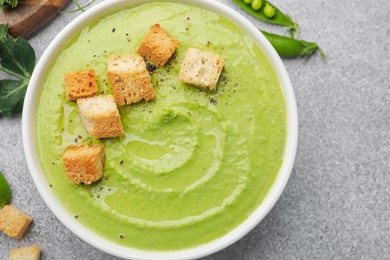 Photo of Tasty pea cream soup with croutons served on grey table, top view