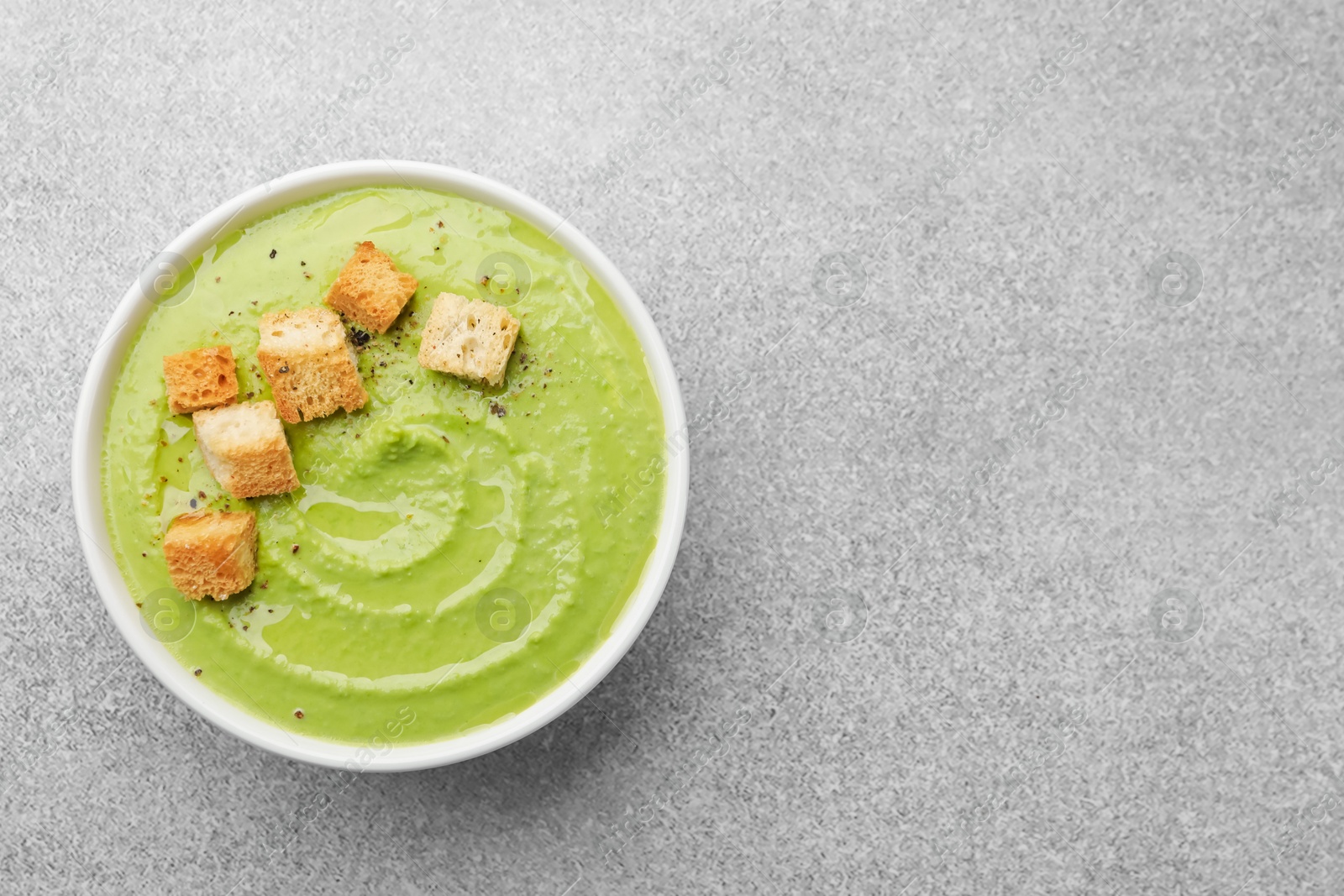 Tasty pea cream soup with croutons on grey table, top view. Space for text Photo of Tasty pea cream soup with croutons on grey table, top view. Space for text