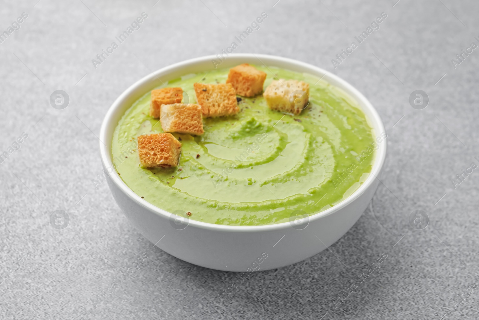Tasty pea cream soup with croutons on grey table, closeup Photo of Tasty pea cream soup with croutons on grey table, closeup