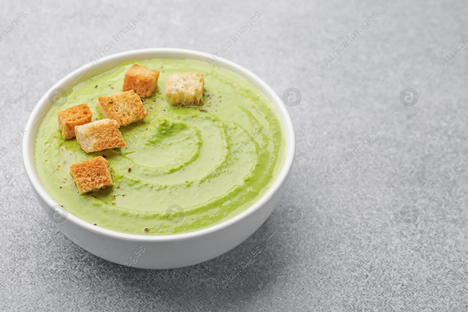 Tasty pea cream soup with croutons on grey table, closeup. Space for text Photo of Tasty pea cream soup with croutons on grey table, closeup. Space for text