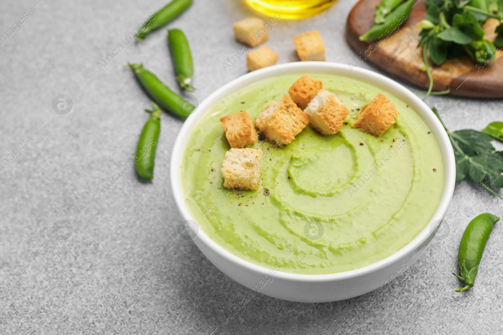 Tasty pea cream soup with croutons served on grey table, closeup Photo of Tasty pea cream soup with croutons served on grey table, closeup