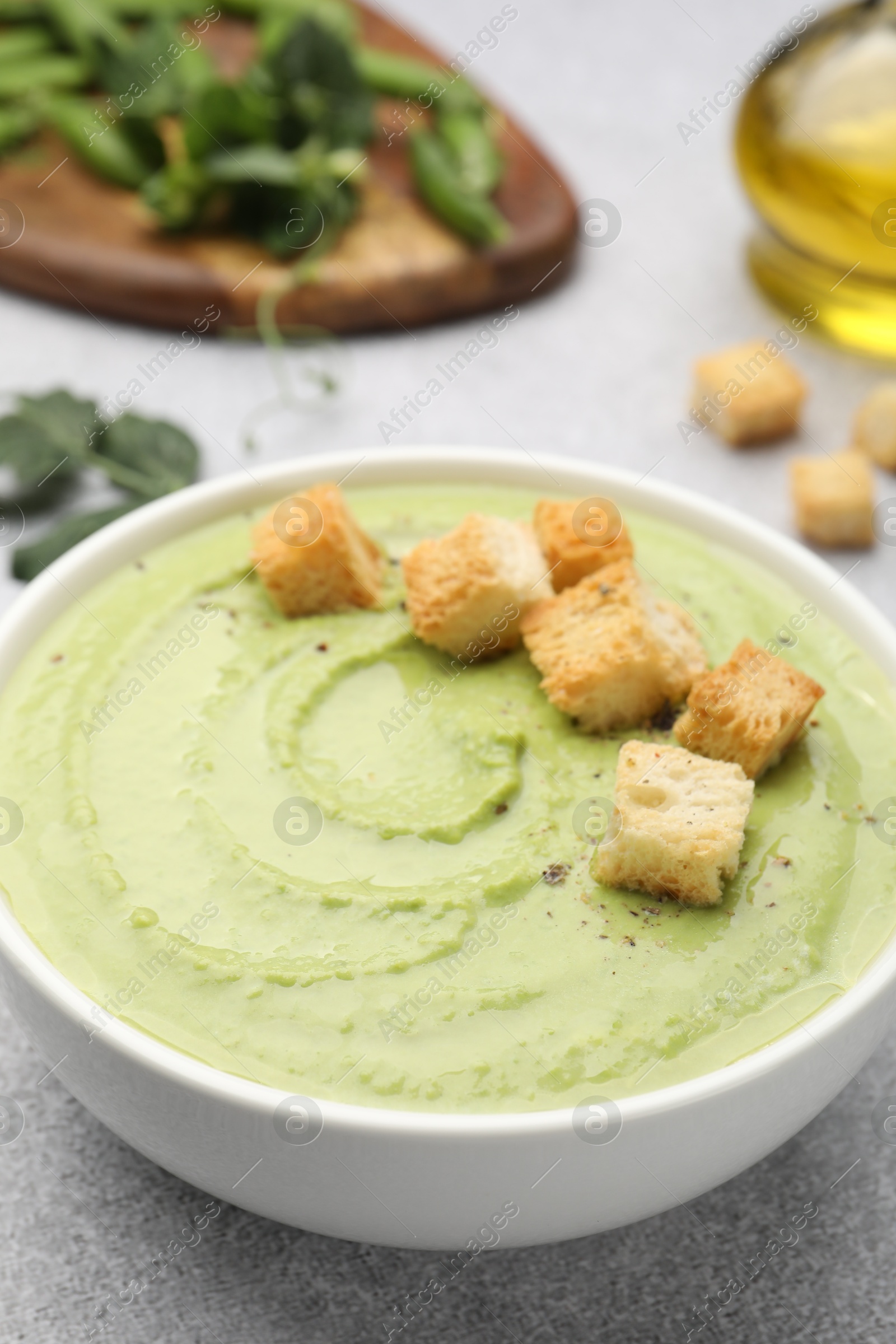 Tasty pea cream soup with croutons served on grey table, closeup Photo of Tasty pea cream soup with croutons served on grey table, closeup