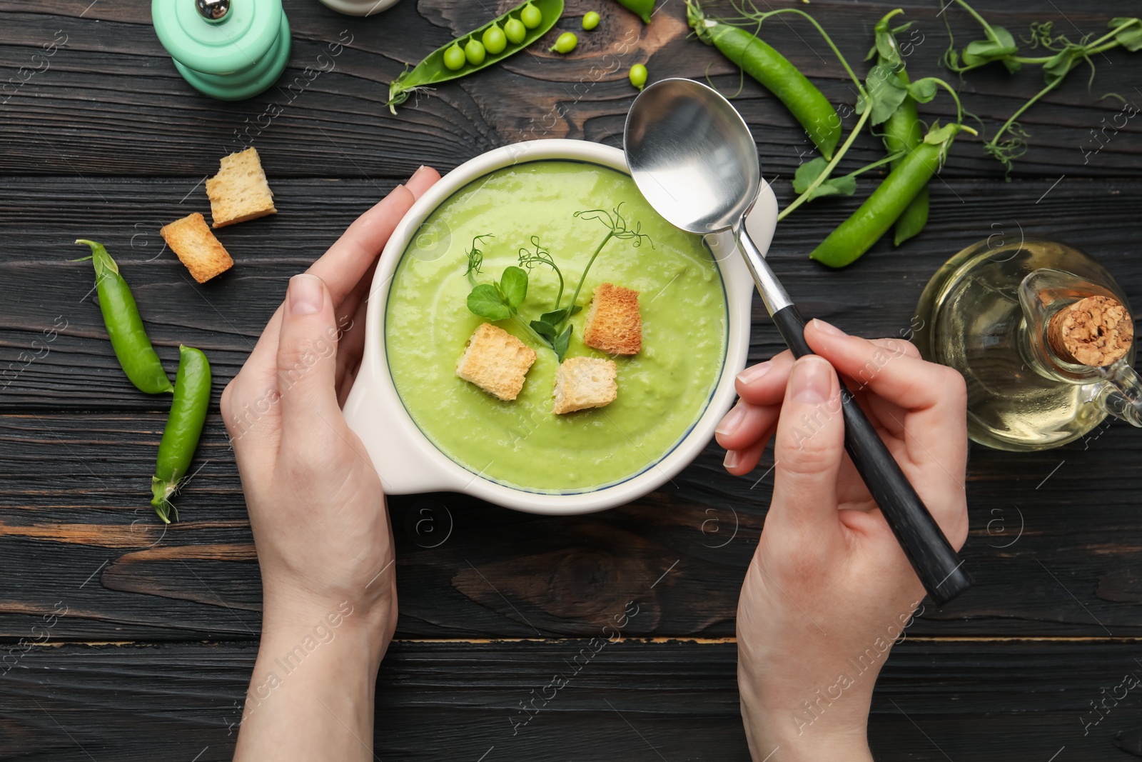 Woman eating tasty pea cream soup at wooden table, top view Photo of Woman eating tasty pea cream soup at wooden table, top view