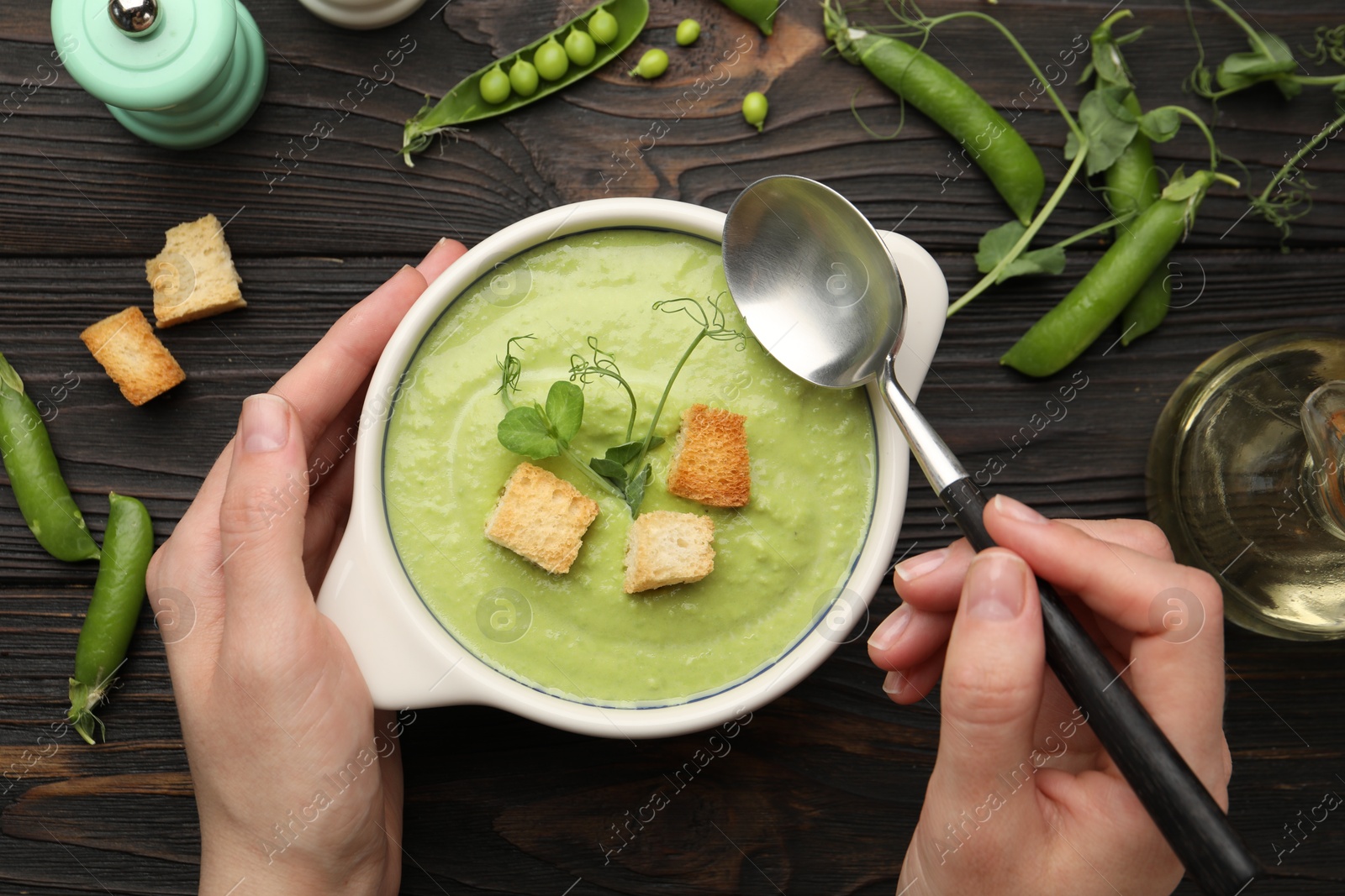 Woman eating tasty pea cream soup at wooden table, top view Photo of Woman eating tasty pea cream soup at wooden table, top view