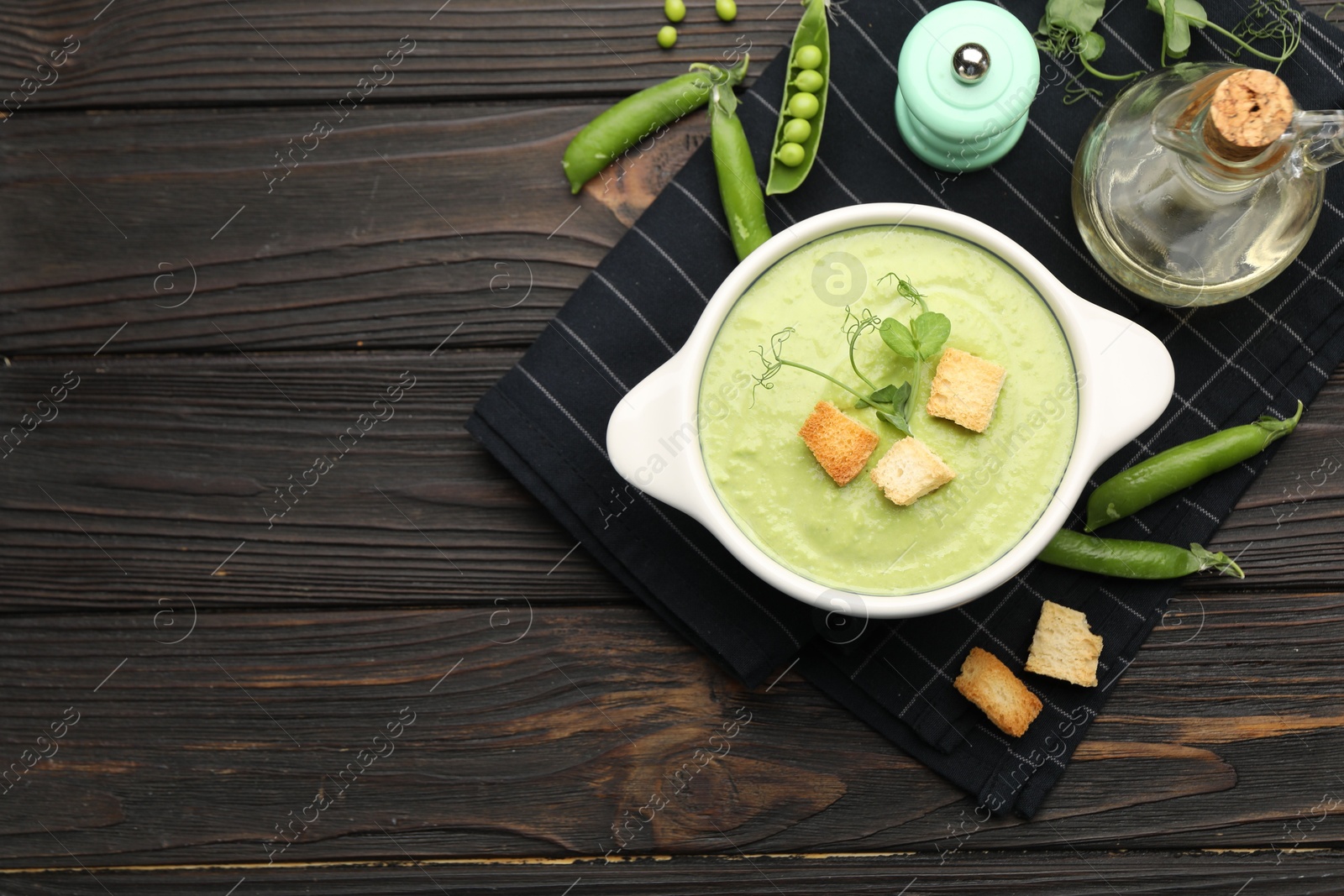 Tasty pea cream soup with croutons served on dark wooden table, flat lay. Space for text Photo of Tasty pea cream soup with croutons served on dark wooden table, flat lay. Space for text