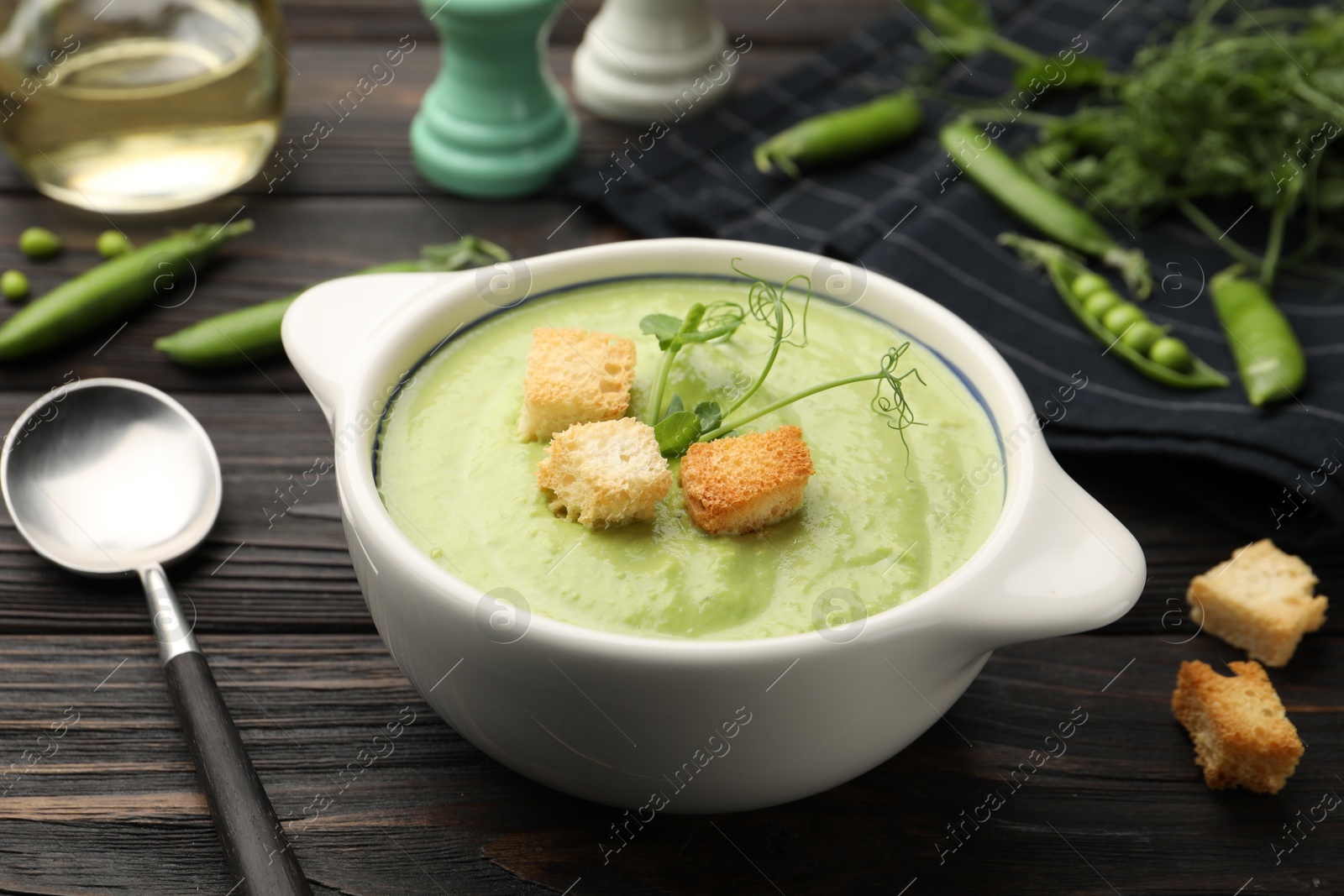 Tasty pea cream soup with croutons served on dark wooden table, closeup Photo of Tasty pea cream soup with croutons served on dark wooden table, closeup