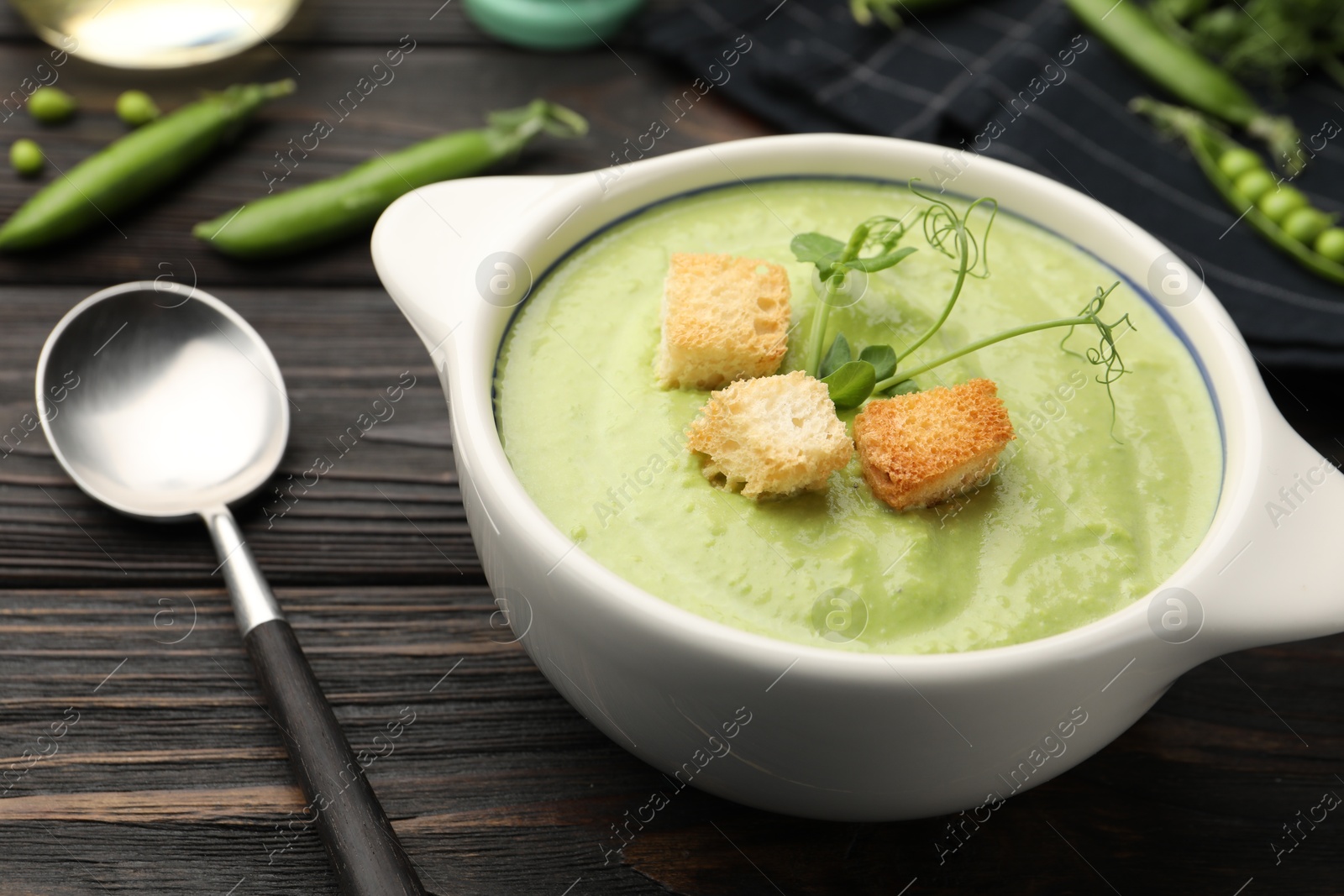 Tasty pea cream soup with croutons served on dark wooden table, closeup Photo of Tasty pea cream soup with croutons served on dark wooden table, closeup