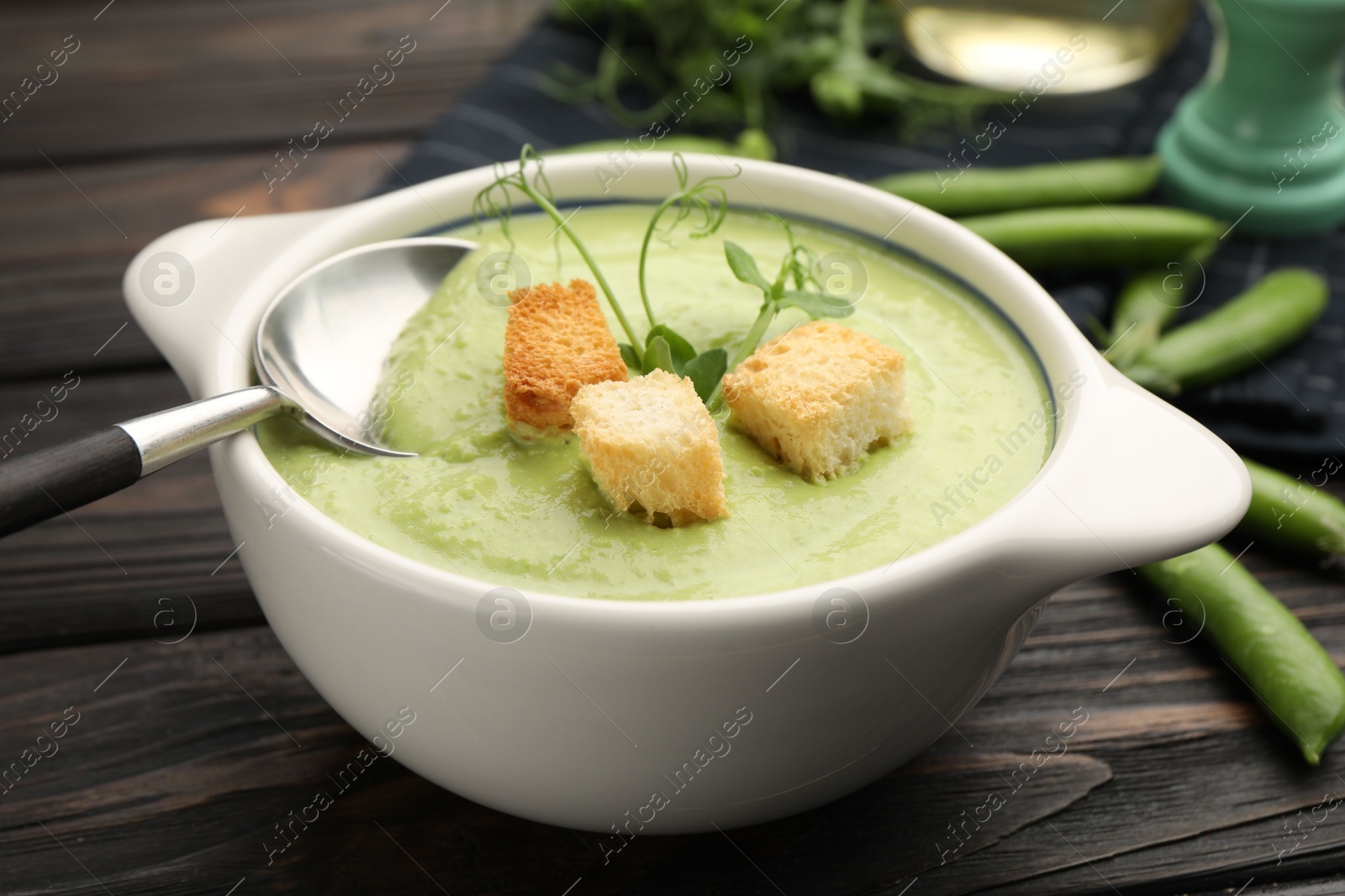 Tasty pea cream soup with croutons served on dark wooden table, closeup Photo of Tasty pea cream soup with croutons served on dark wooden table, closeup