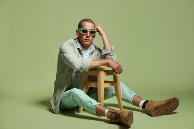 Photo of Fashionable portrait of handsome man in stylish outfit on green background