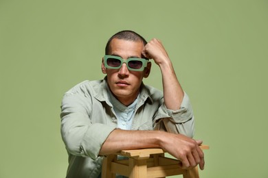 Photo of Fashionable portrait of handsome man in stylish outfit on green background