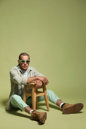Photo of Fashionable portrait of handsome man in stylish outfit on green background
