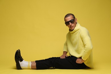 Photo of Fashionable portrait of handsome man in stylish outfit on yellow background