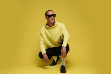Photo of Fashionable portrait of handsome man in stylish outfit on yellow background