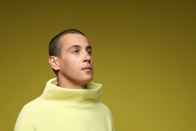 Photo of Fashionable portrait of handsome man in stylish outfit on olive background, space for text