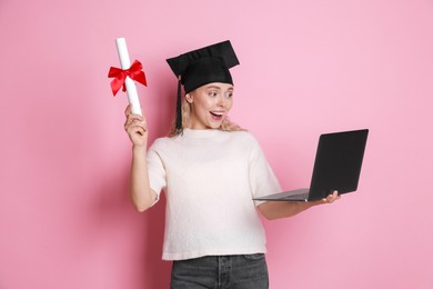 Photo of Happy student with diploma and laptop after graduation on pink background