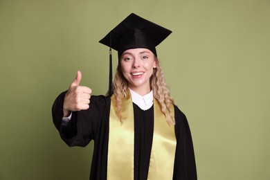 Photo of Happy student showing thumbs up after graduation on green background