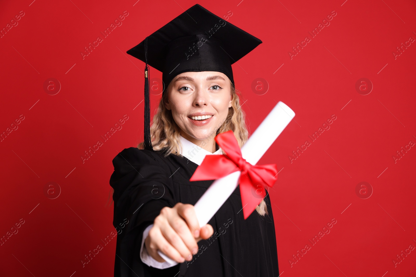 Happy student with diploma after graduation on red background, selective focus Photo of Happy student with diploma after graduation on red background, selective focus