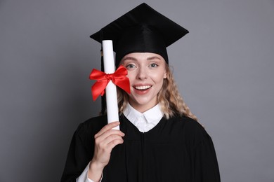 Photo of Happy student with diploma after graduation on grey background